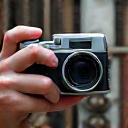 A professional photographer capturing a detail of industrial architecture with a vintage camera.